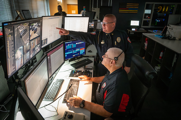 NC State police chief Daniel House, standing, works with folks at Campus Safety Center. NC State Emergency Management and Mission Continuity (EMMC) and NC State University Police work together with campus partners to improve campus safety procedures, technology and systems.