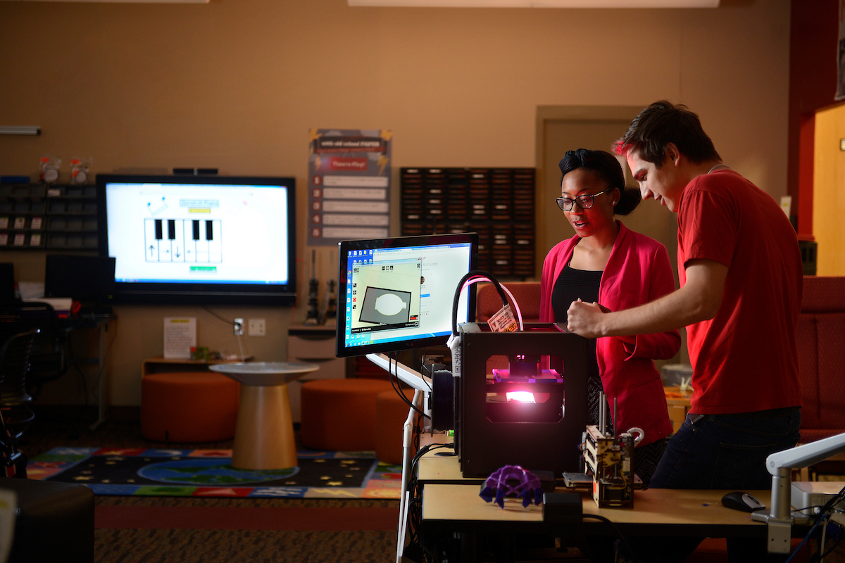 College of education students work in the library at Poe Hall with a Makerbot 3D printer.