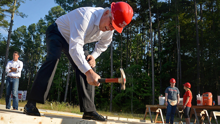 Chancellor Randy Woodson swings a hammer prior to the Build-A-Block Habitat for Humanity project ceremony.