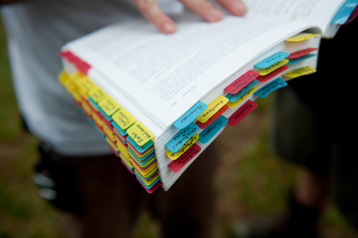 A student holding a book with colored tabs for different species of birds
